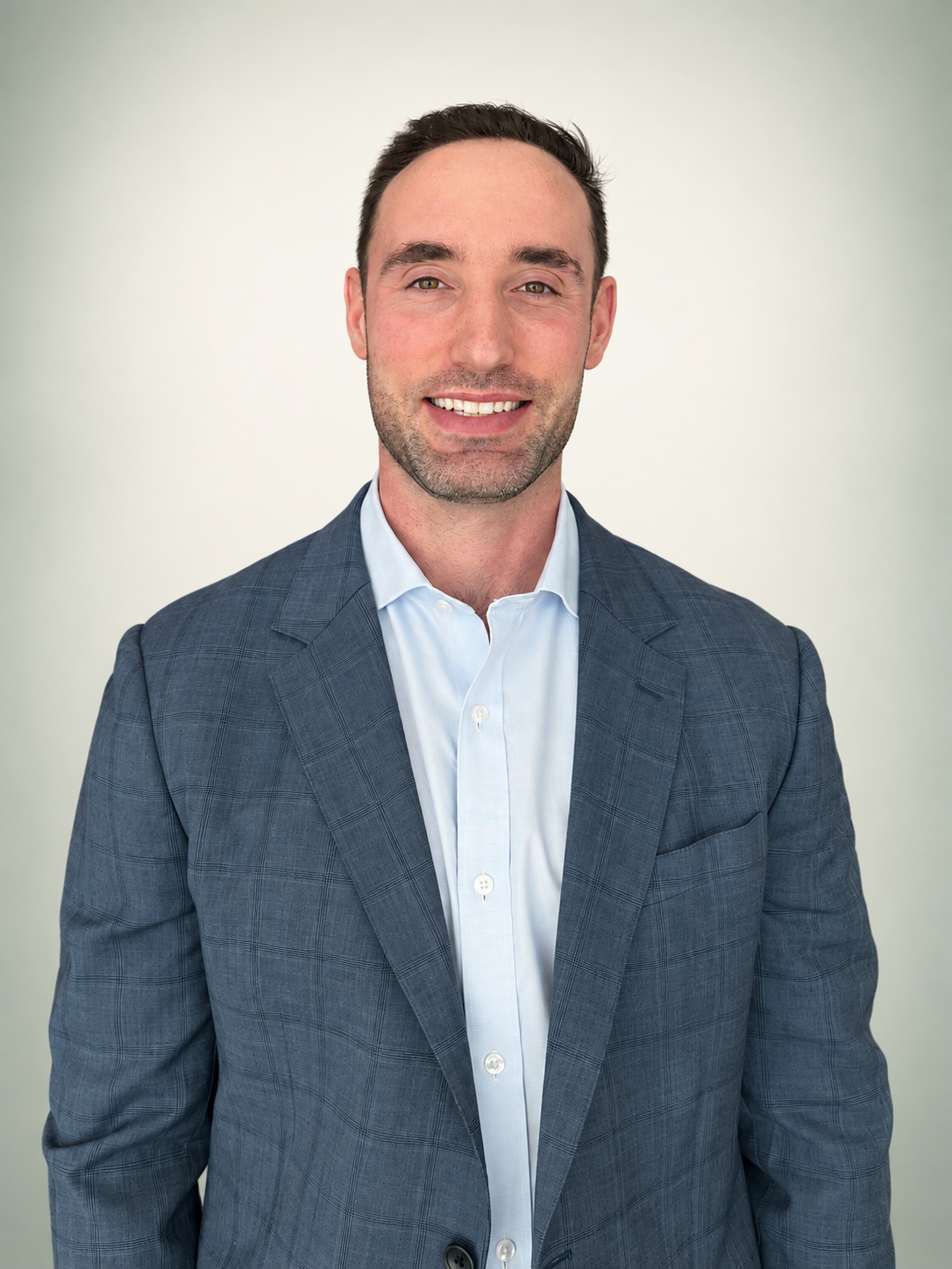 Brian Abatemarco smiling in a blue blazer against an ivory and sage studio background